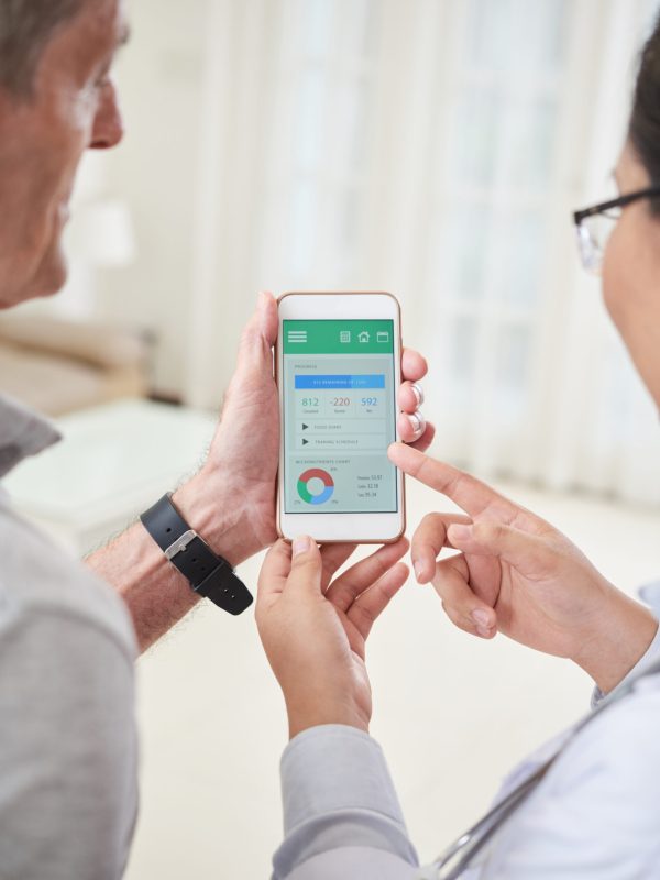 Crop doctor holding smartphone and showing application for healthy lifestyle during home visit